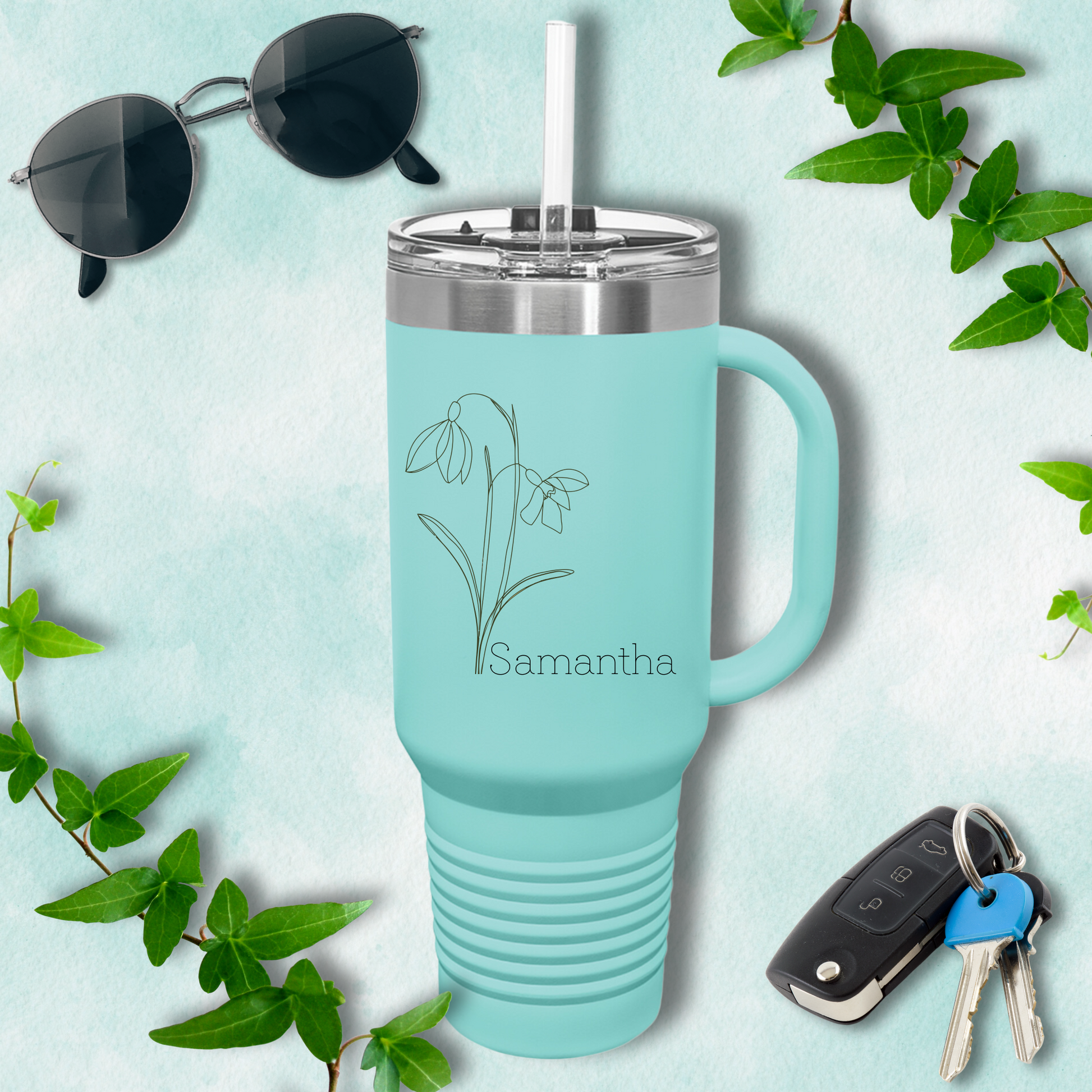 a blue mug with a flower on it next to a pair of sunglasses and keys