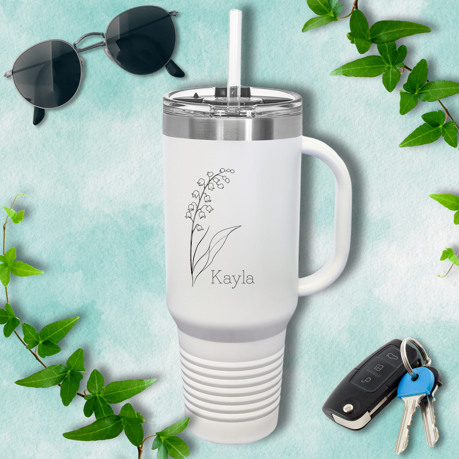 a travel mug with a keychain, sunglasses, and keys on a blue