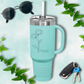 a blue travel mug with a flower on it next to a pair of sunglasses and