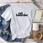 a white shirt that says cat hearder next to a cup of coffee