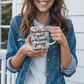 a woman holding a coffee mug with a quote on it