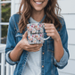 a woman holding a coffee mug that says thank you