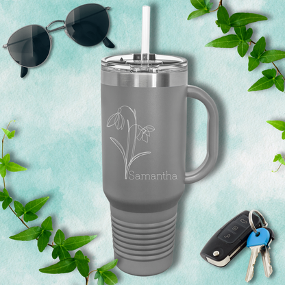 a gray travel mug with a flower on it next to a pair of sunglasses and