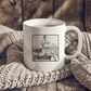 a white coffee mug sitting on top of a blanket